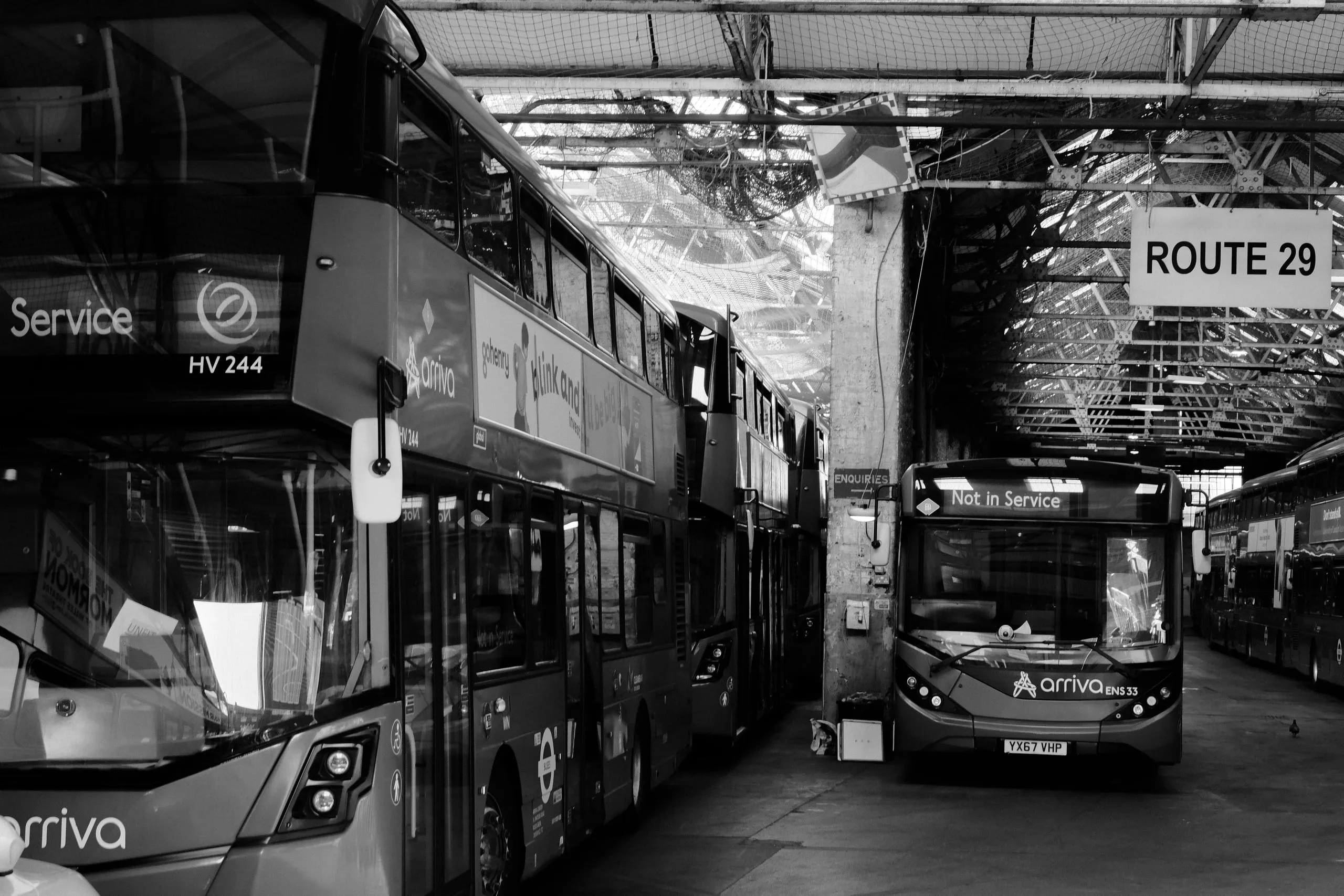 Double-deckers stood in rows inside the garage under a glass roof, their destination boards reading Not in Service, beneath a Route 29 sign.