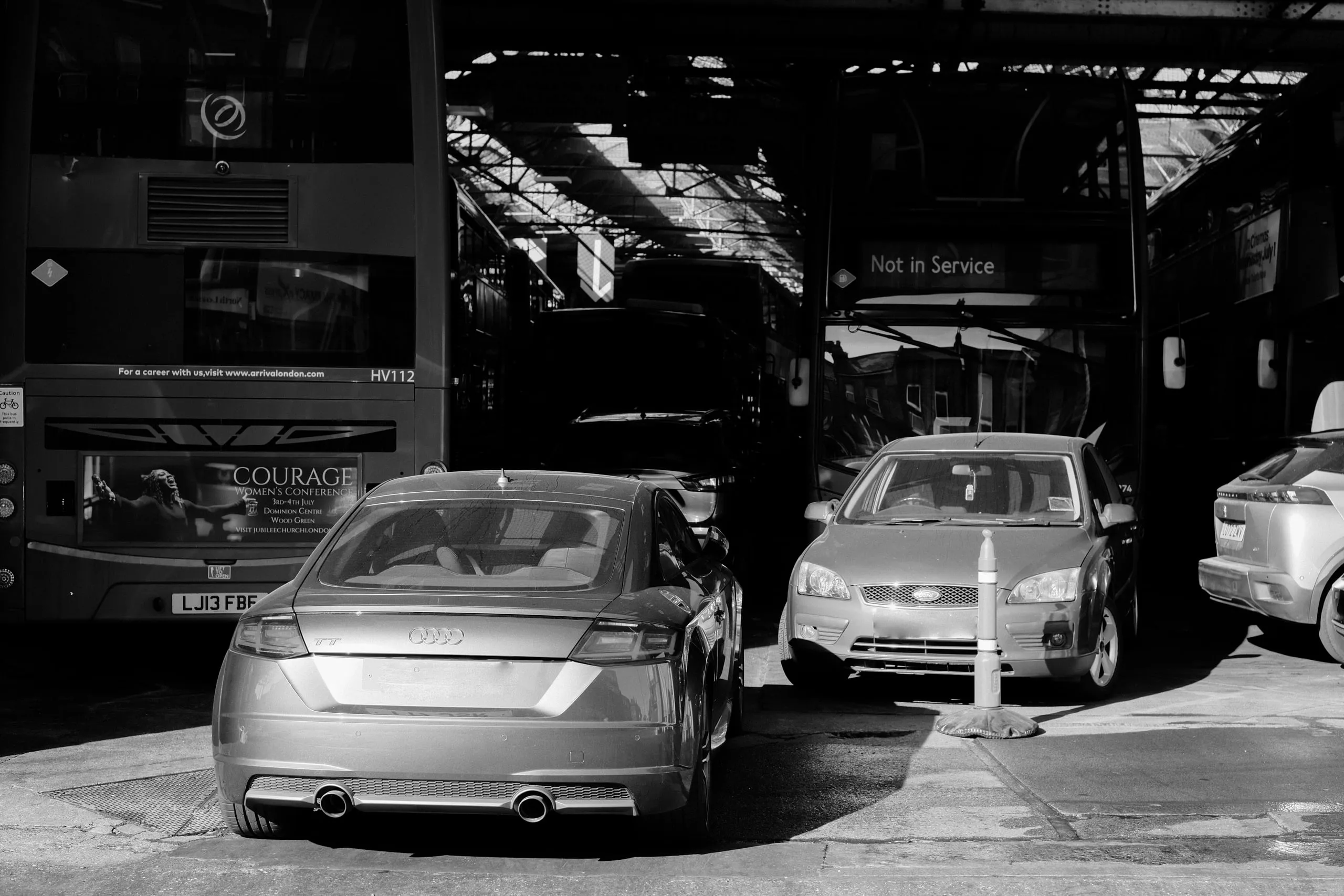 Private cars parked tight across the mouth of the garage, buses stood behind them in the dark of the shed.